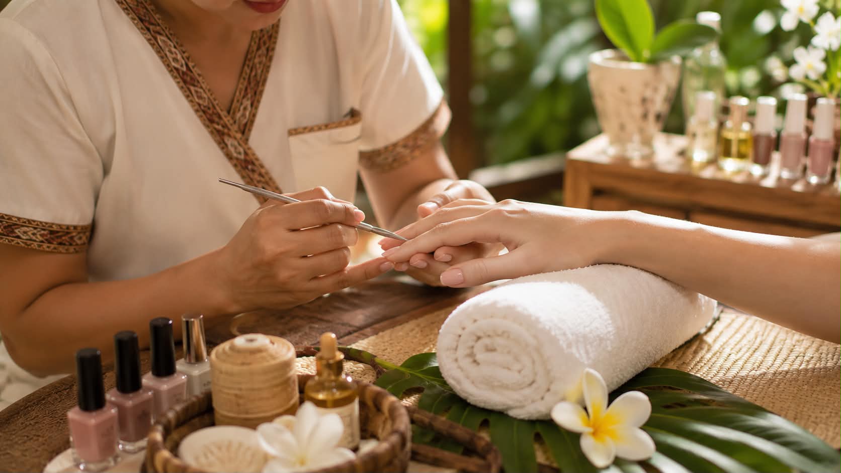 A manicure in progress, with polish bottles and a rolled towel.
